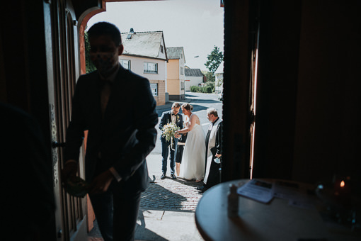 Braut und Bräutigam aus der geöffneten Kirchentür fotografiert