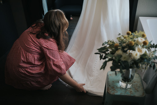 Braut richtet den Saum ihres Hochzeitskleides.