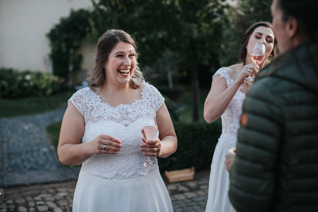 Lachende Braut mit Rosé in der Hand.