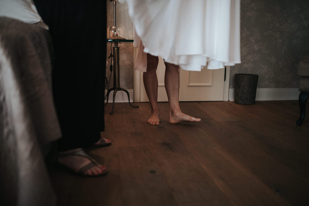 Beine der Braut beim Anziehen des Brautkleides