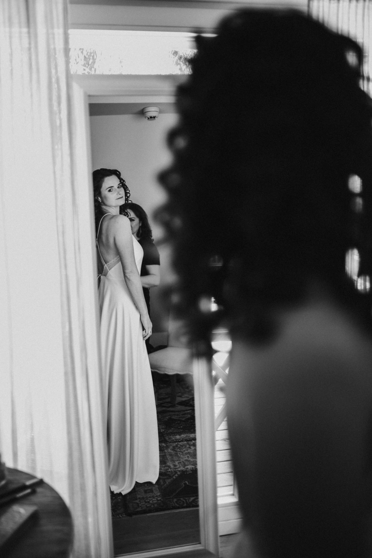 Braut betrachtet sich im Spiegel in ihrem Brautkleid