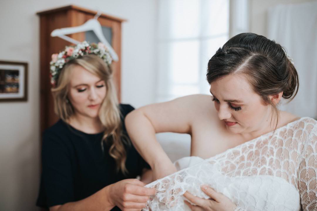 Trauzeugin hilft der Braut beim Anziehen des Kleides