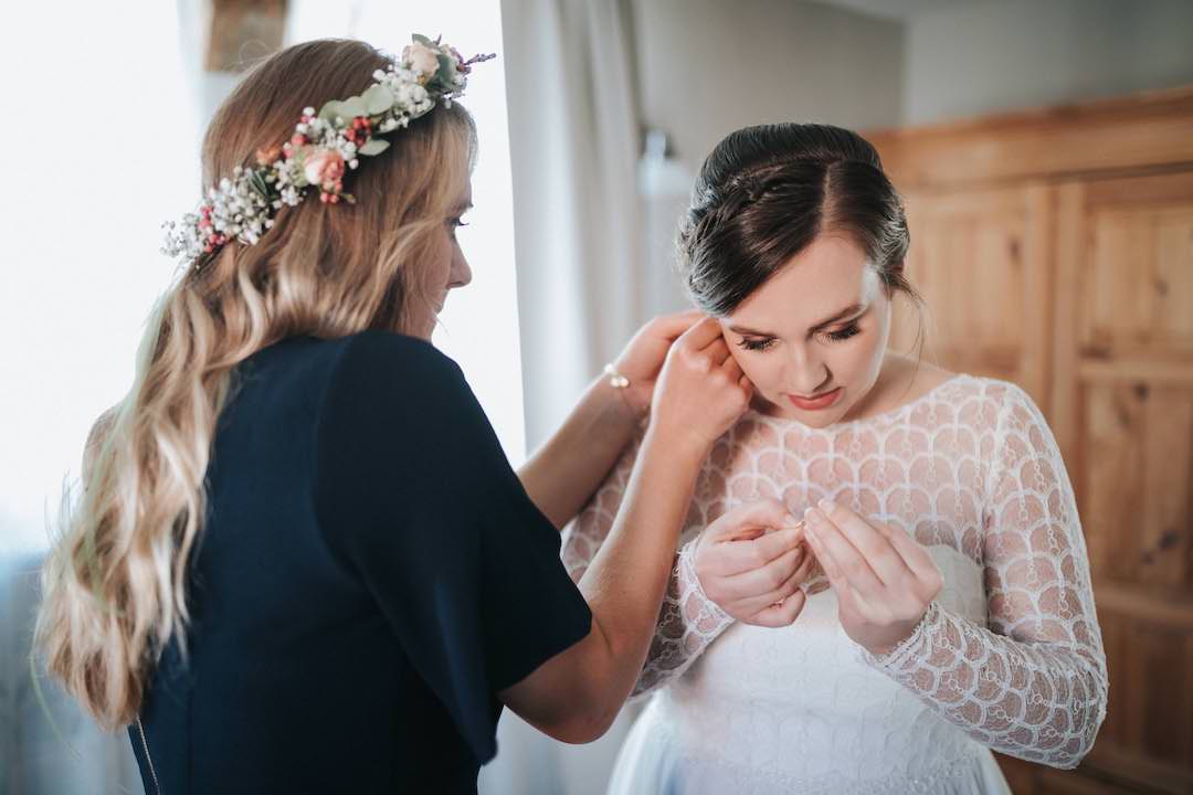 Trauzeugin hilft der Braut die Ohrringe anzulegen