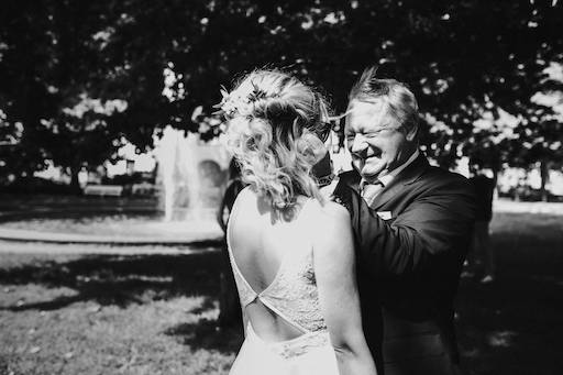 Der Vater sieht seine Tochter das erste Mal im Brautkleid und lacht herzlich.