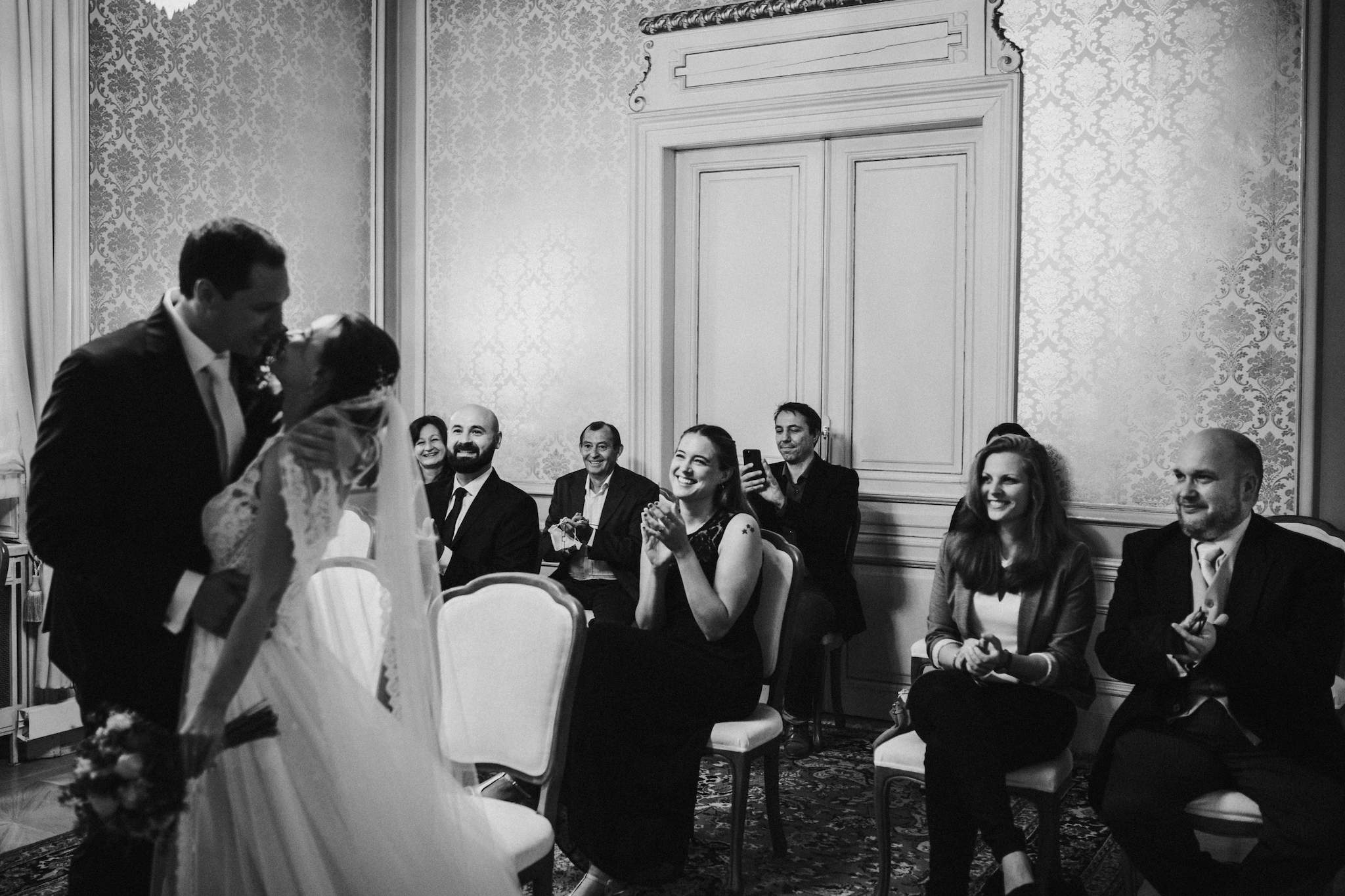 Hochzeitsgesellschaft applaudiert zum ersten Kuss des Brautpaares.